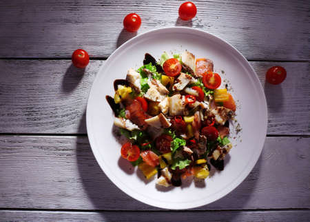 Fresh fish salad with vegetables on plate on wooden table close-upの写真素材