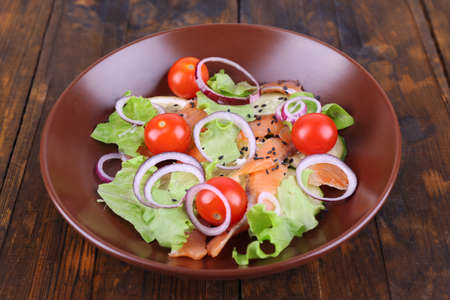 Fresh fish salad with vegetables on plate on wooden table close-upの写真素材