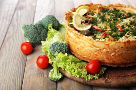 Vegetable pie with broccoli, peas, tomatoes and cheese on wooden backgroundの写真素材