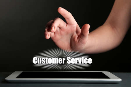 Hand touching tablet screen and Customer Service text on dark backgroundの写真素材