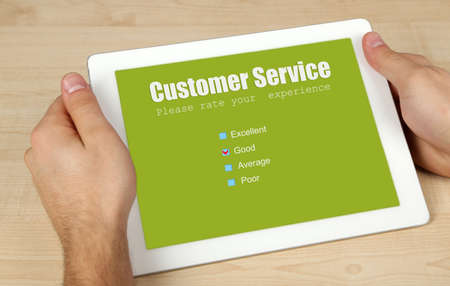 Hands holding tablet PC with Customer Service text on screen on wooden table backgroundの写真素材