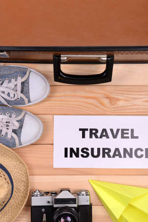 Suitcase and tourist stuff with inscription travel insurance on wooden background top viewの写真素材
