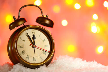 Alarm clock in snow on bright backgroundの写真素材