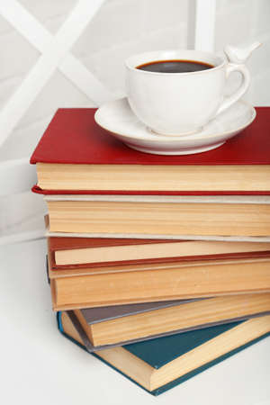 Pile of books with cup of hot drink on the chair on brick wall backgroundの写真素材