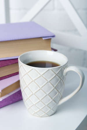 Pile of books with cup on the chair on brick wall backgroundの写真素材