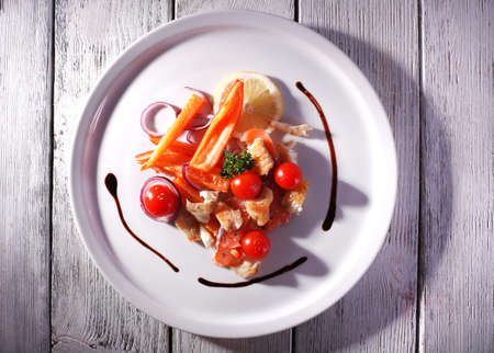 Fresh fish salad with vegetables on plate on wooden table close-upの写真素材