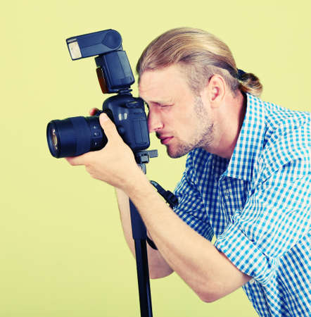 Handsome photographer with camera on monopod, on green backgroundの写真素材