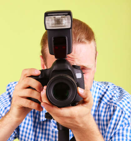 Handsome photographer with camera on monopod, on green backgroundの写真素材