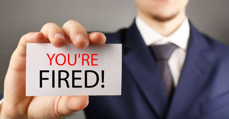 Businessman holding card with text You are firedの写真素材