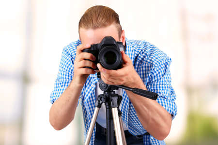 Handsome photographer with camera on tripod indoorsの写真素材