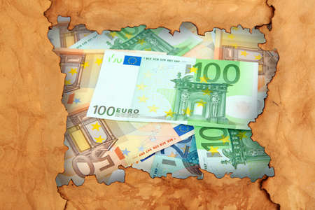 Euro banknotes through torn craft paperの写真素材