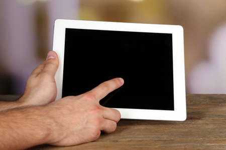 Hands holding tablet PC on wooden table and light blurred backgroundの写真素材