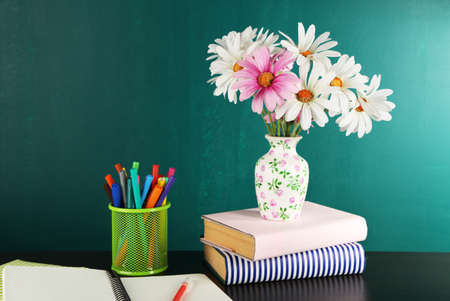 Composition on desk with books and flowers on green blackboard backgroundの写真素材