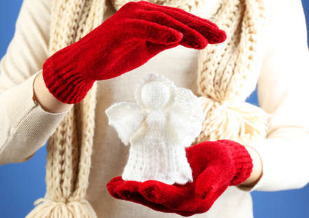 Knitted Christmas angel in female hand on color backgroundの写真素材