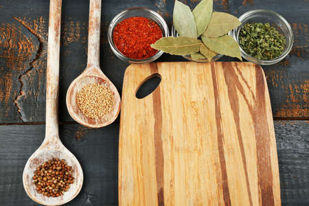 Different spices and herbs with cutting board on color wooden table backgroundの写真素材