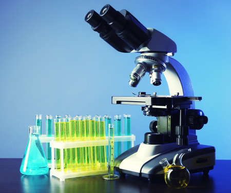 Microscope and test tubes on table, on color backgroundの写真素材