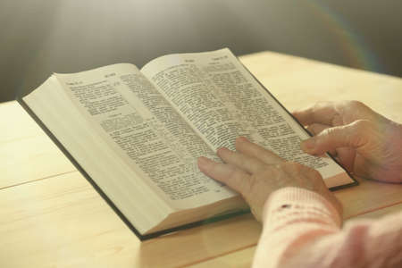 Hands of old woman with Bible on table, close-upの写真素材