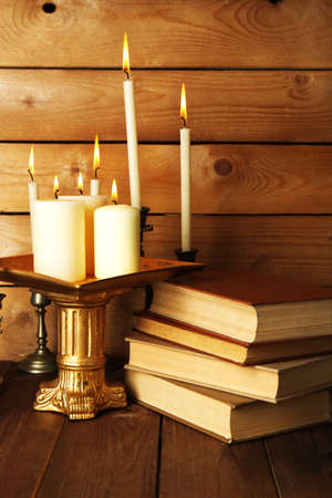 Retro candlesticks with candles and books, on wooden backgroundの写真素材