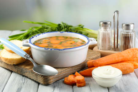 Composition with carrot soup, ingredients and herbs on color wooden table, on light backgroundの写真素材