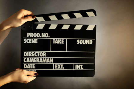 Movie clapper in female hand on dark color backgroundの写真素材