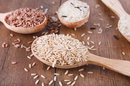Different kinds of rice in spoons on wooden backgroundの写真素材