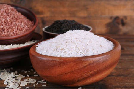 Different kinds of rice in bowls on wooden backgroundの写真素材