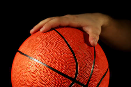Basketball player holding ball, on dark backgroundの写真素材
