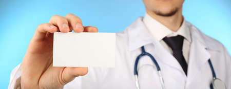 Male doctor with card on blue backgroundの写真素材