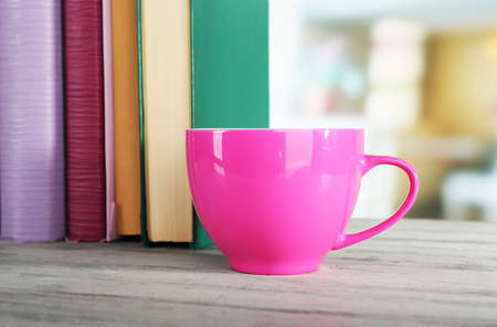 Color cup of drink with books on wooden surface and light backgroundの写真素材