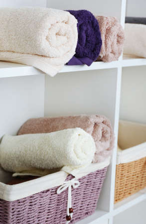 Rolled towels with wicker basket son shelf of rack backgroundの写真素材