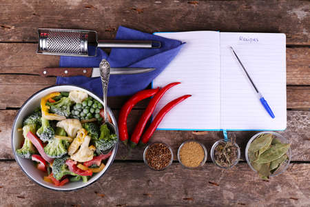 Frozen vegetables and blank notebook, on wooden table backgroundの写真素材