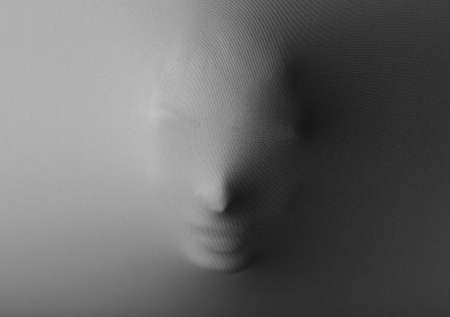 Screaming human face pressing through fabric as horror backgroundの写真素材