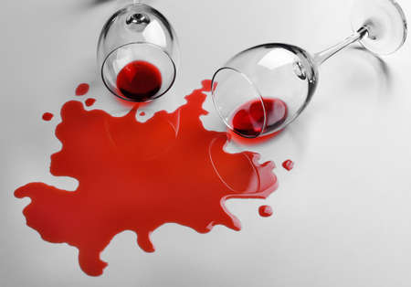 Red wine spilled from glass on white backgroundの写真素材