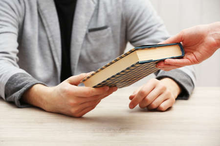 Author signing autograph in own book at wooden table on white planks backgroundの写真素材