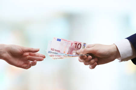 Businessman giving money on light blurred backgroundの写真素材