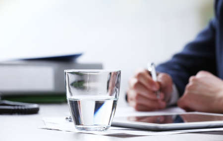 Businessman working at table in office on white blurred backgroundの写真素材