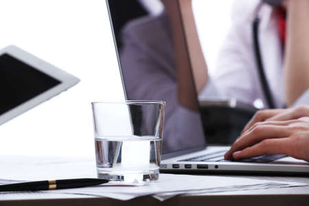 Working with laptop at worktable on white blurred backgroundの写真素材