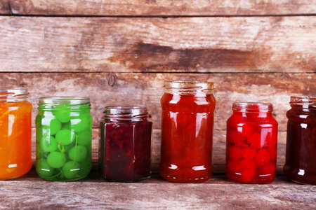 Homemade jars of fruits jam on rustic wooden backgroundの写真素材