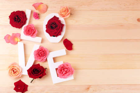 Beautiful roses with word LOVE on wooden backgroundの写真素材