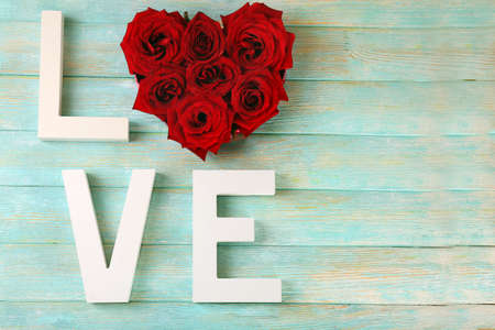 Beautiful roses with word LOVE on color wooden planks backgroundの写真素材