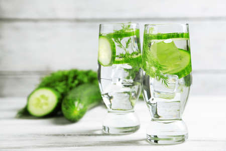 Glasses with fresh organic cucumber water on wooden tableの写真素材