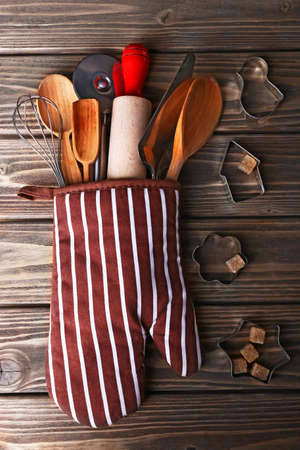 Set of kitchen utensils in mitten on wooden planks backgroundの写真素材