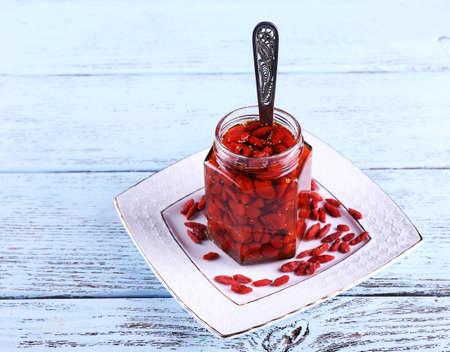 Jar of goji berry jam on plate on wooden backgroundの写真素材