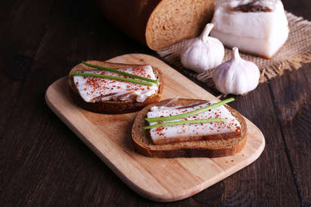 Sandwiches with lard on cutting board and garlic on wooden backgroundの写真素材