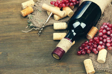 Bottle of wine, grapes and corks on wooden backgroundの写真素材