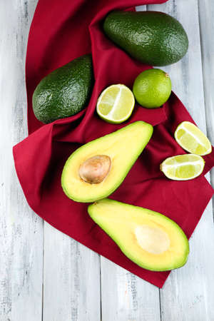 Avocado with limes on napkin on wooden の写真素材