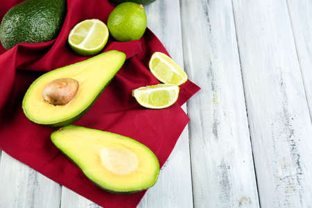 Avocado with limes on napkin on wooden の写真素材