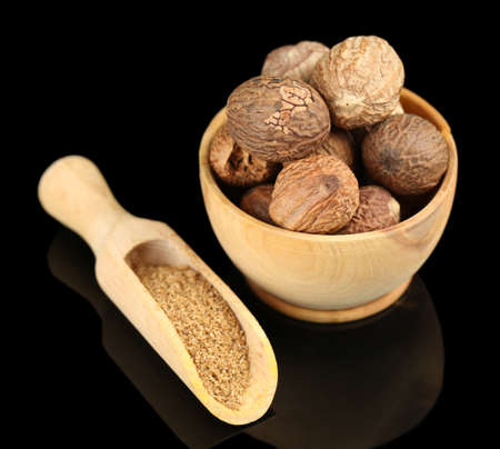 Nutmeg in wooden bowl, isolated on blackの写真素材