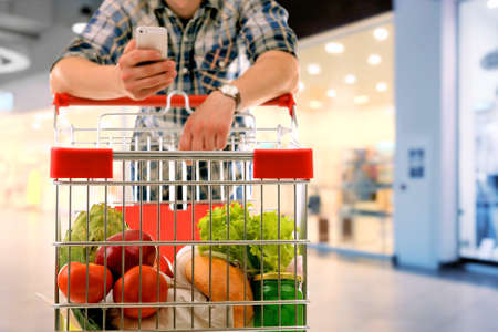 Young man with shopping cart in storeの写真素材