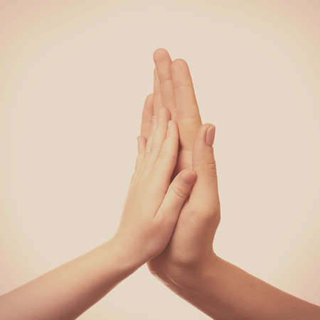 Child and mother hands together on light backgroundの写真素材